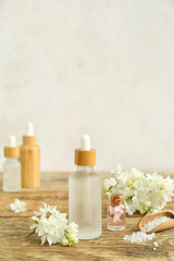 Fototapeta na wymiar Bottles of cosmetic oil with beautiful lilac flowers and sea salt on wooden table