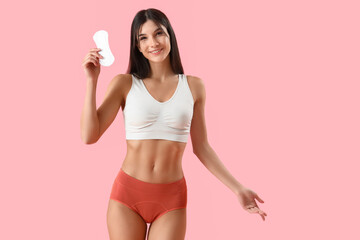 Young woman in menstrual panties with pad on pink background