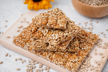 Plate with tasty kozinaki and sunflower seeds on white background