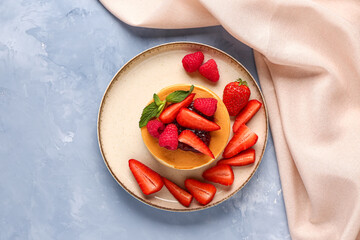 Plate with tasty pancakes and berries on blue background