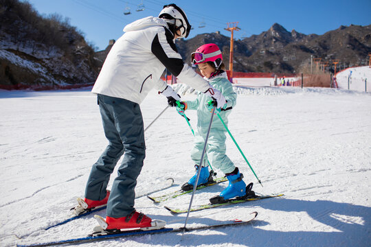 Little girl learning how to ski with her coach