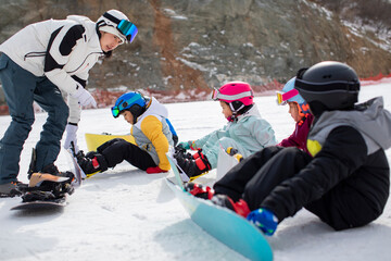 Children learning how to snowboard with their coach
