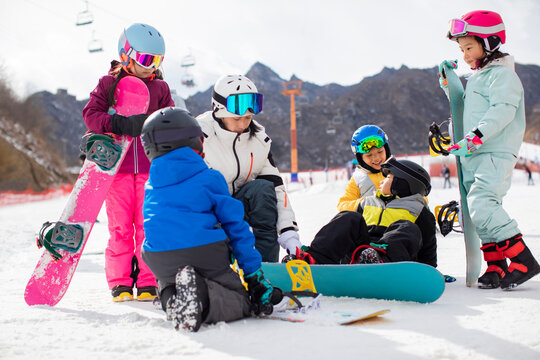 Children learning how to snowboard with their coach
