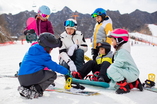 Children learning how to snowboard with their coach