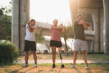 Woman exercising in a park with a friend providing support while using a prosthetic leg. People jogging side by side outside in a park. Female walking and exercise works out outside. - obrazy, fototapety, plakaty