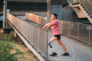 Woman wearing prosthetic equipment jogging in a park. Female walking and exercise works out outside.