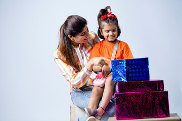 Indian mom and daughter with gift boxes on white background.