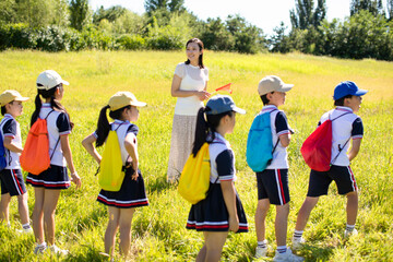 Cheerful school children relaxing in park with their teacher