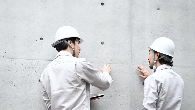 ビルのコンクリートの点検指を差して確認やメンテナンスをする作業員たちの動画