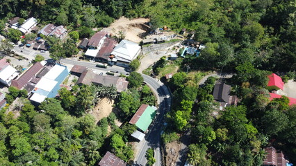 An impressive aerial view of a winding asphalt road with numerous houses and trees around it. The bird's-eye view offers a unique perspective on the surrounding environment.