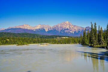 Pyramid mountain looms over this panoramic view of the fast flowing Athabasca river near Jasper in the Canada rockies - obrazy, fototapety, plakaty