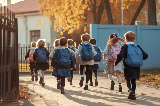 rearview of Little kids schoolchildren pupils students running hurrying to the school building for classes lessons from to the school bus