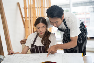 Young Asian designers looking at blueprints together in their workshop.