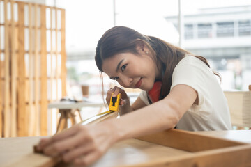 Happy female carpenter working at workshop. She preparing to design her furniture.