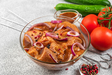 Marinated meat with fresh vegetables, bbq sauce, pepper, onion and basil in a bowl with skewers for cooking barbecue