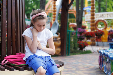 sad little girl sitting alone in the amusement park