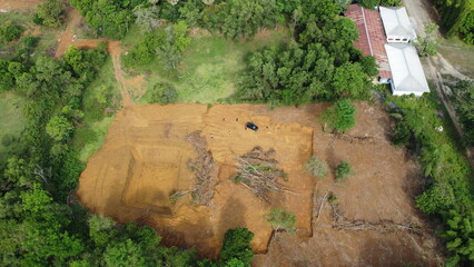 A stunning aerial view of land clearing where the brown soil contrasts with the green trees surrounding it. The sight captures the beauty and destruction of human activity on the environment.