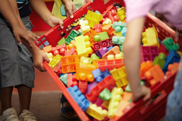 Closeup, hands and kids with plastic blocks, colors and playing with fun, games and education. Zoom, children or young people in a classroom, school and playful with child development, box and creche