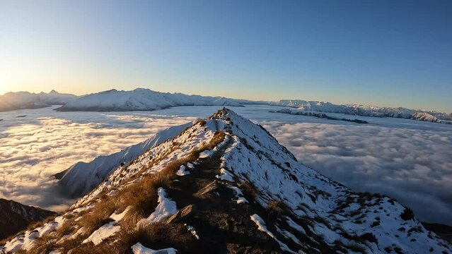 POV hiking along alpine ridge in New Zealand above clouds snowy mountains cinematic 4K travel footage