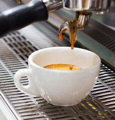 Coffee machine, restaurant and espresso or hot drink in a cup at a small business on counter top. Kitchen, cafe and pouring latte or caffeine at shop with preparation with electrical appliance.