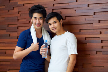 Happy, portrait and gay couple at the gym with water on a break from a workout together. Smile,...