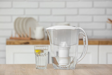 Water filter jug with glass on table in modern kitchen