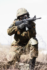 Soldier man, machine gun and outdoor with aim, field and nature for war, fight and army in...