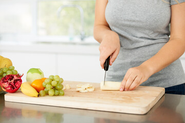 Woman hands, cooking and fruit for health food and nutrition for weight loss diet and health at home. Kitchen, fruits and chopping banana in a house with breakfast and nutritionist in the morning