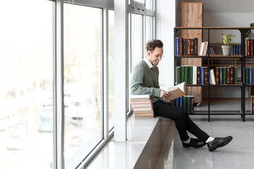 Young man reading book in library