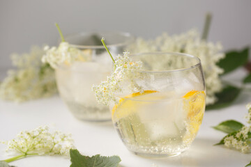A summer drink made of elderflowers and lemon with ice on a light background