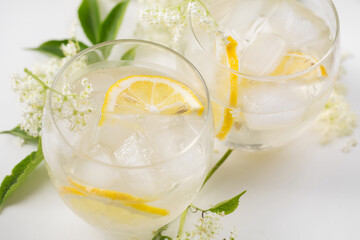 A drink made of elderflowers and lemon with ice on a light background - obrazy, fototapety, plakaty