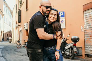 Portrait of happy    smiling  Couple at Bologna . Casual couple portrait outdoors, tourist in Italy Happy Bearded man  kissing and hugging  Brunette woman  on the streets of Italy 