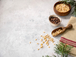Flat lay of pine nuts in a bowl and wooden scoop  on a napkin on a light texture background with...