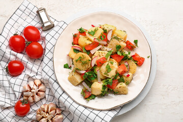 Plate of tasty Potato Salad with vegetables and ingredients on light background