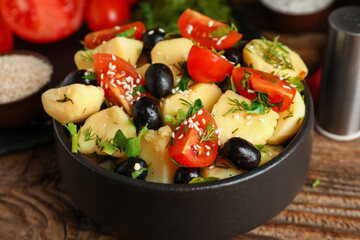 Bowl of tasty Potato Salad with vegetables on wooden background, closeup