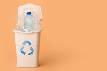 Container for garbage with plastic on beige background. Recycling concept