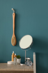 Bath accessories with mirror on shelf near blue wall