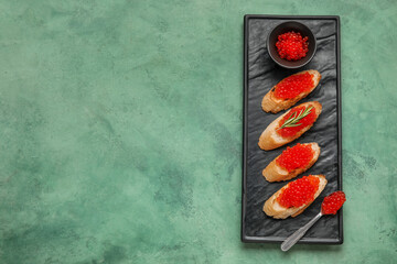 Obraz na płótnie Canvas Tasty bruschettas with red caviar on green background