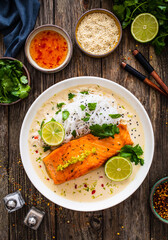 Creamy coconut lime salmon with rice noodles on wooden table