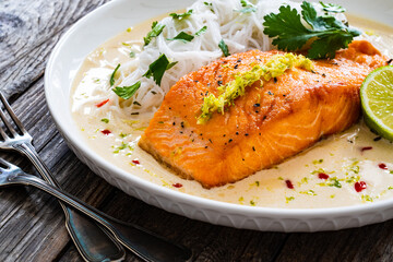 Creamy coconut lime salmon with rice noodles on wooden table