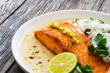Creamy coconut lime salmon with rice noodles on wooden table