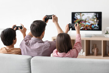 Father with his little children playing video game at home, back view