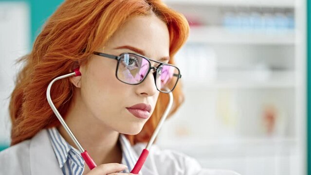 Young redhead woman doctor examining with stethoscope at clinic