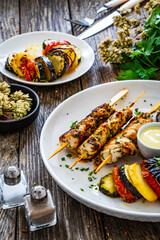 Greek chicken souvlaki with Greek style roasted vegetable casserole on wooden background