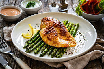 Grilled chicken breast and green asparagus on wooden table