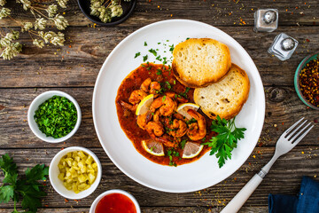 Louisiana style shrimp in hot sauce with bread on wooden table