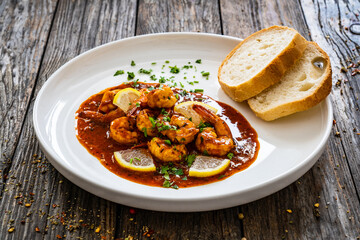 Louisiana style shrimp in hot sauce with bread on wooden table