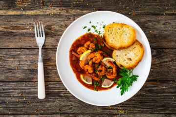 Louisiana style shrimp in hot sauce with bread on wooden table