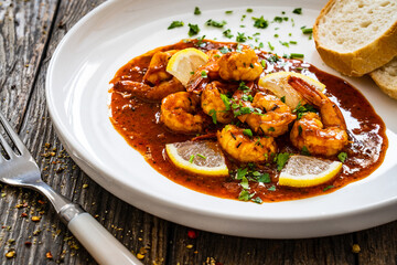 Louisiana style shrimp in hot sauce with bread on wooden table