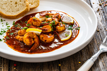 Louisiana style shrimp in hot sauce with bread on wooden table